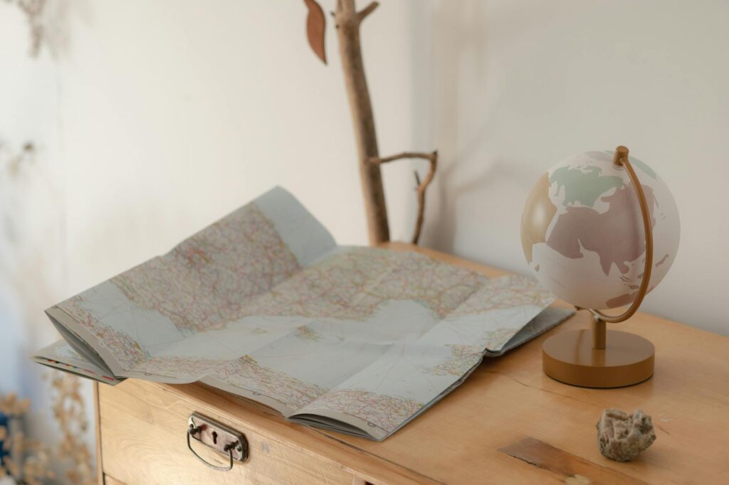Cozy setting of a vintage map and globe on a wooden table, symbolizing travel exploration.